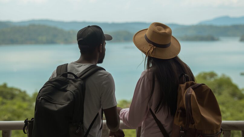 Two African American travelers looking out from a beach house in Rwanda.