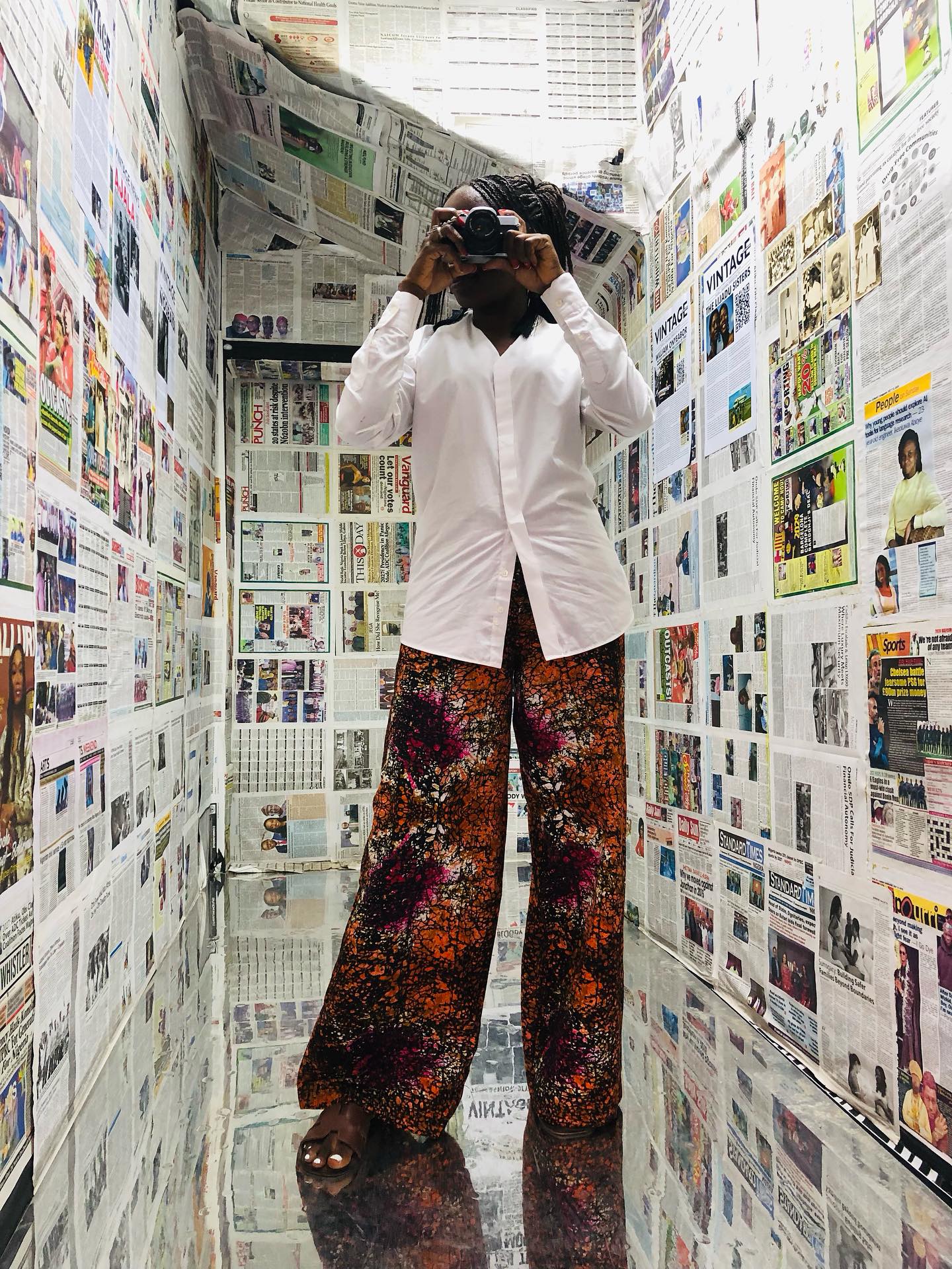 A female visitor at Illusion Zone Lagos with a camera and traditional attire.
